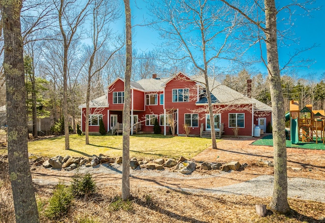 rear view of property featuring a yard and a playground