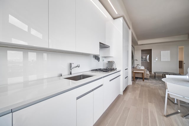 kitchen with sink, white cabinetry, light hardwood / wood-style flooring, and stainless steel gas cooktop