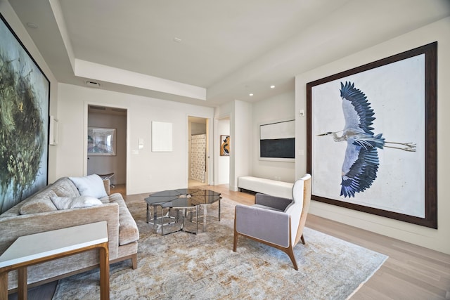 living room featuring a tray ceiling and light wood-type flooring