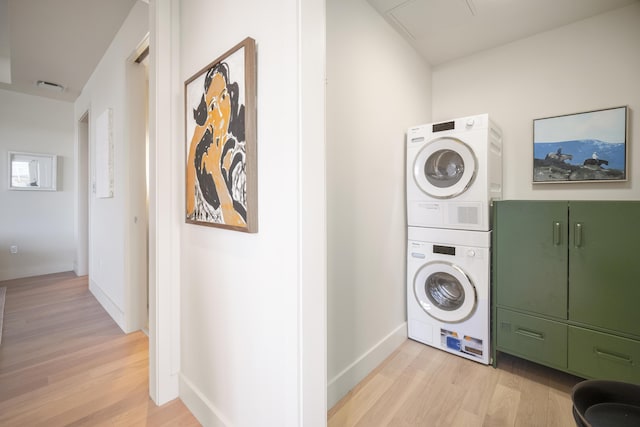 clothes washing area featuring stacked washer / drying machine and light wood-type flooring