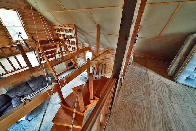 staircase with wood walls and vaulted ceiling