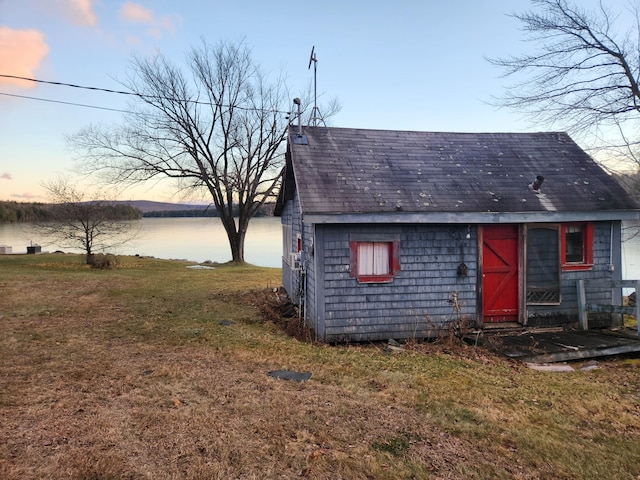 outdoor structure at dusk featuring a yard and a water view