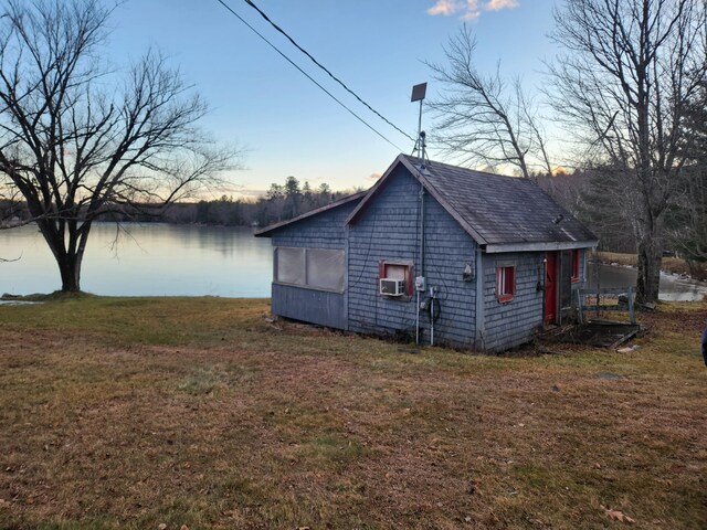 back house at dusk featuring a yard and a water view