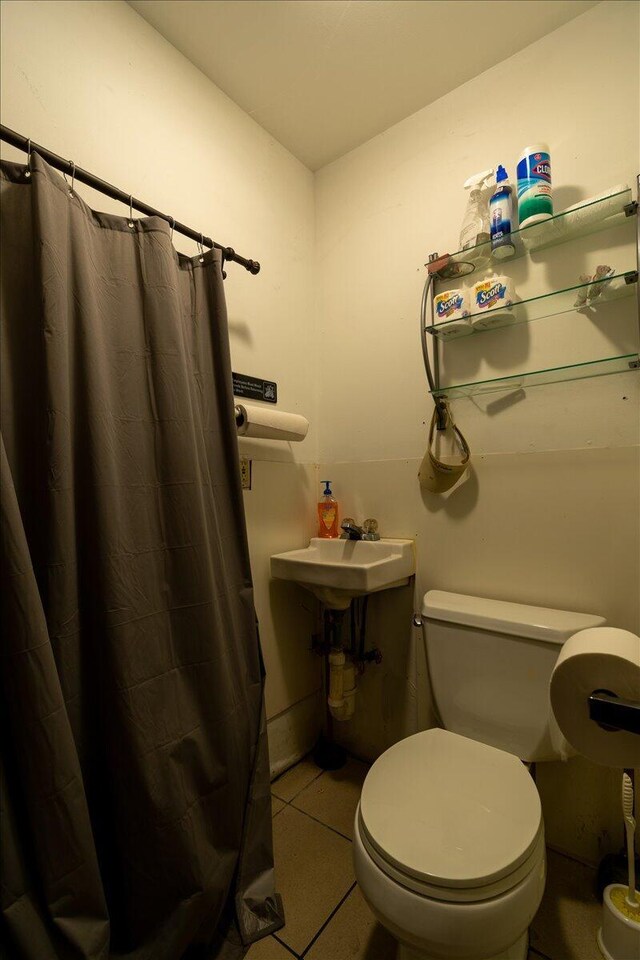 bathroom featuring toilet, curtained shower, and tile patterned floors