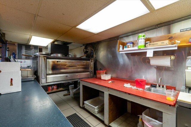 kitchen with a paneled ceiling, sink, and light tile patterned floors