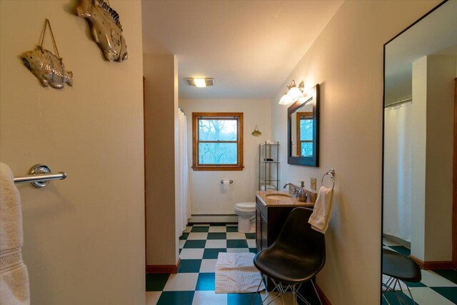 bathroom featuring toilet, a baseboard heating unit, and vanity