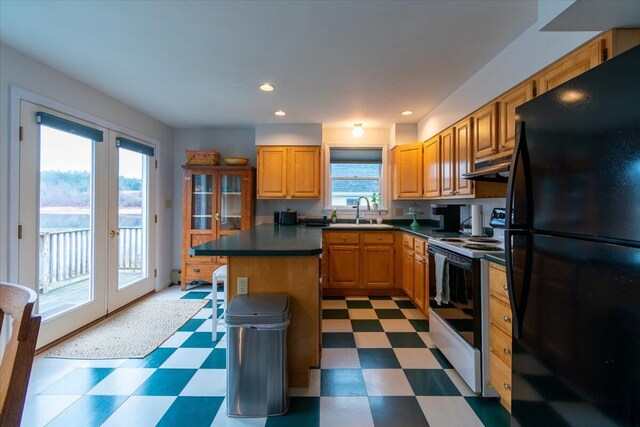 kitchen featuring electric range, a center island, a healthy amount of sunlight, black fridge, and sink