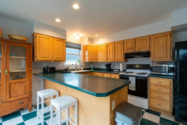 kitchen featuring white range with electric cooktop, a kitchen breakfast bar, kitchen peninsula, black fridge, and sink