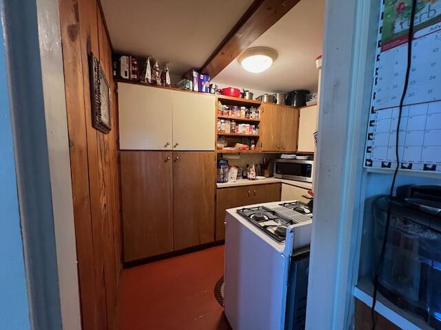 kitchen featuring beam ceiling, decorative backsplash, and white gas range oven