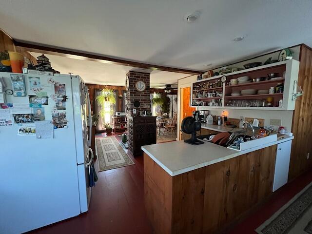 kitchen with white fridge, kitchen peninsula, and dark hardwood / wood-style floors