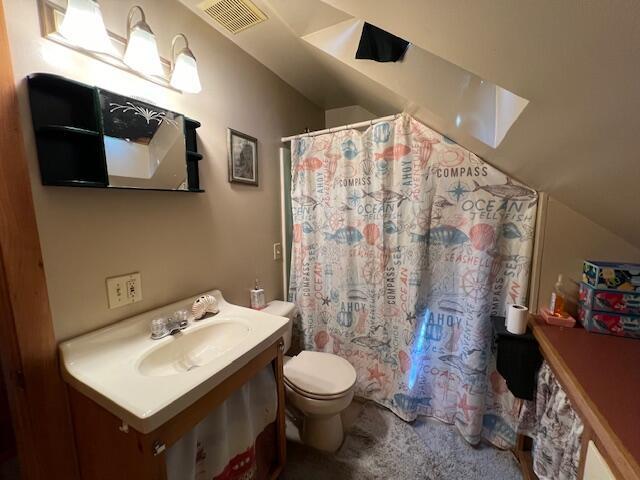 bathroom featuring toilet, a shower with shower curtain, and sink