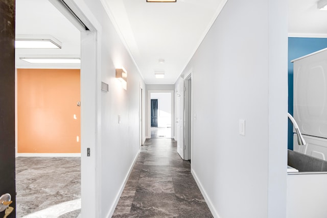 hall featuring ornamental molding and stacked washer / dryer