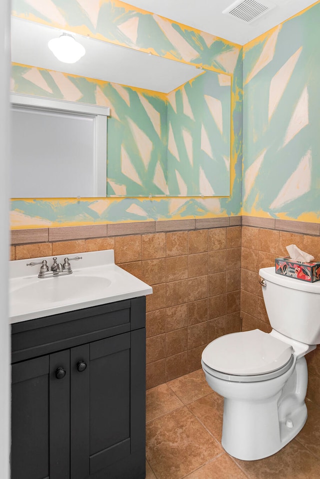 bathroom with vanity, tile patterned flooring, tile walls, and toilet