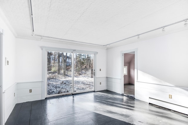 spare room with rail lighting and a baseboard heating unit