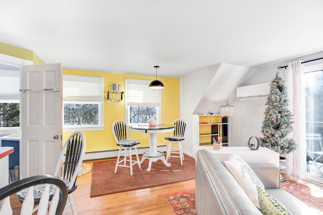 dining space featuring an AC wall unit, baseboard heating, and light hardwood / wood-style floors