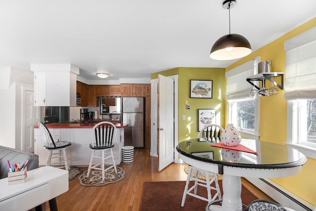 kitchen featuring a baseboard radiator, hardwood / wood-style floors, and stainless steel refrigerator