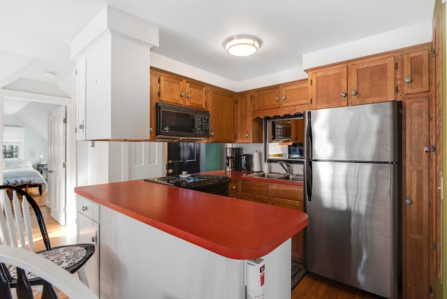 kitchen featuring sink, range, stainless steel refrigerator, and kitchen peninsula