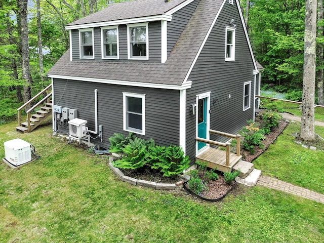 rear view of house with ac unit and a yard