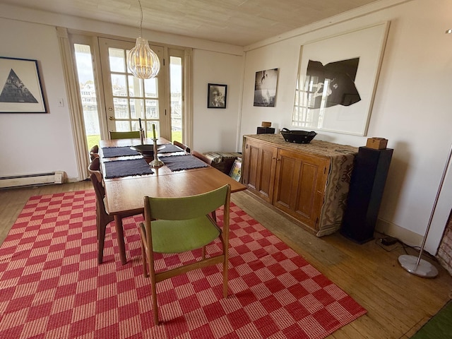 dining space with wood finished floors, a baseboard radiator, and a chandelier
