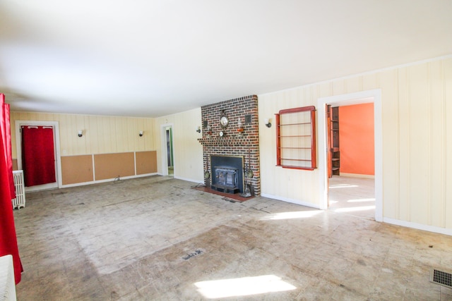 unfurnished living room featuring brick wall, a brick fireplace, and radiator