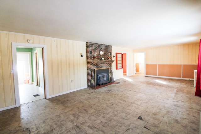 unfurnished living room with tile flooring, brick wall, a brick fireplace, and wood walls