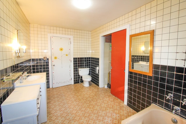 bathroom with tile flooring, vanity, toilet, and tile walls