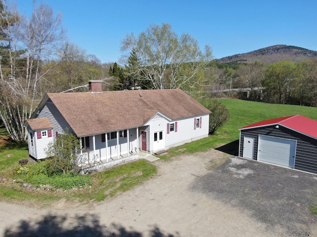 view of front of home featuring a front lawn, an outdoor structure, a mountain view, and a garage