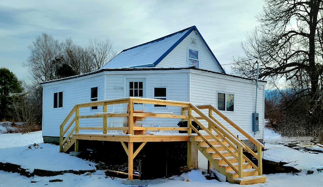 snow covered rear of property with a wooden deck