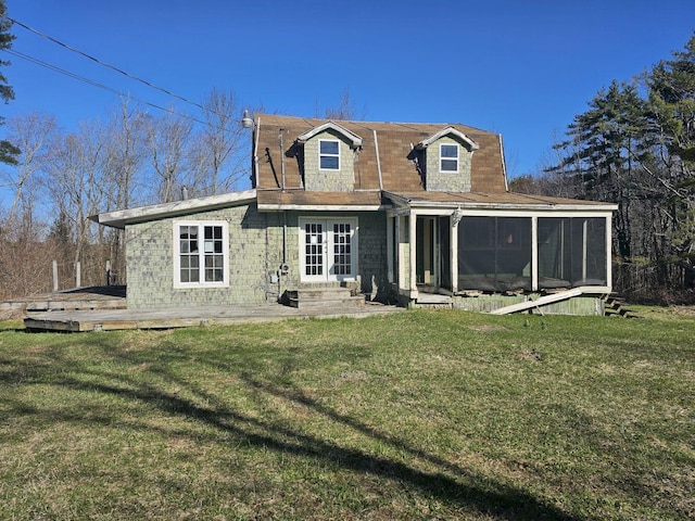 rear view of house featuring a sunroom and a lawn