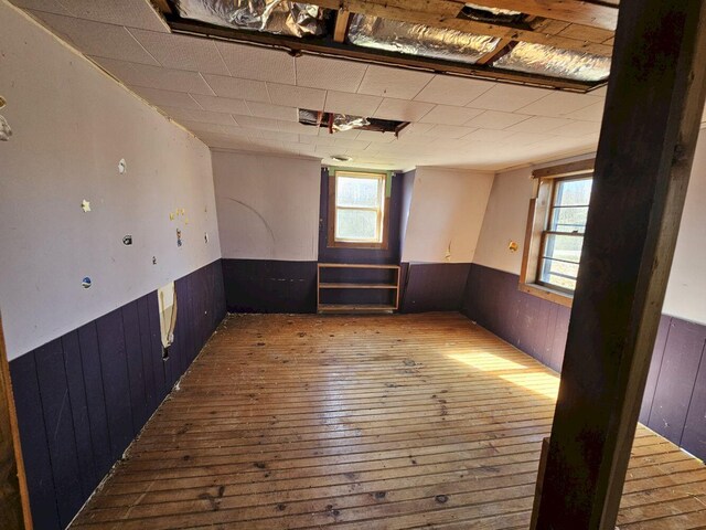 empty room with wood-type flooring, a healthy amount of sunlight, and wood walls