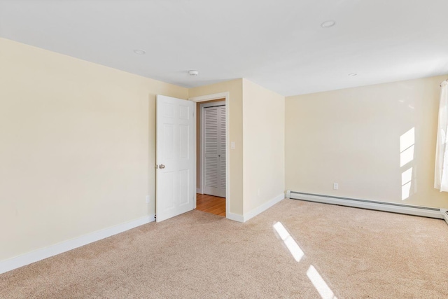 unfurnished bedroom featuring baseboard heating, a closet, and light carpet