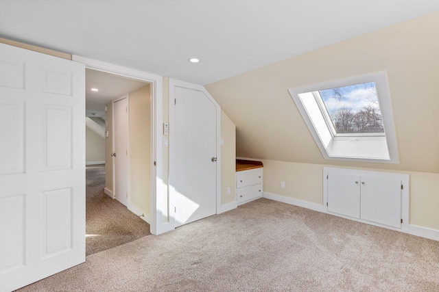 bonus room with vaulted ceiling with skylight and light colored carpet