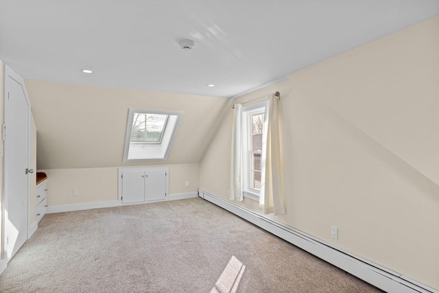 additional living space with a baseboard radiator, lofted ceiling with skylight, light colored carpet, and plenty of natural light