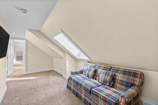 living area with light carpet and vaulted ceiling with skylight