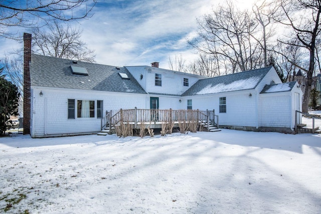 snow covered back of property with a deck