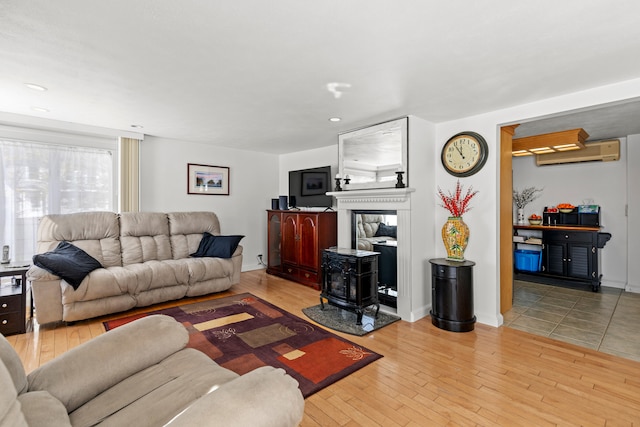 living room with light hardwood / wood-style floors, a wall unit AC, and a wood stove