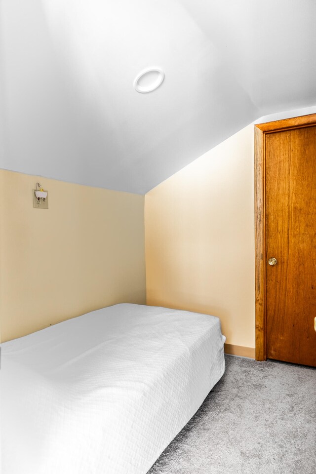 bedroom featuring light colored carpet and lofted ceiling