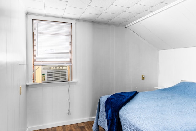 bedroom featuring cooling unit, wood walls, vaulted ceiling, and dark hardwood / wood-style floors