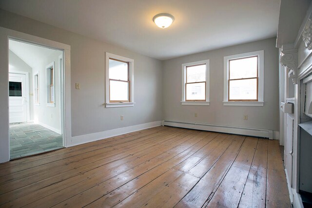 spare room featuring wood-type flooring and baseboard heating