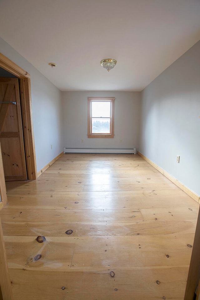 empty room with light hardwood / wood-style floors and a baseboard heating unit