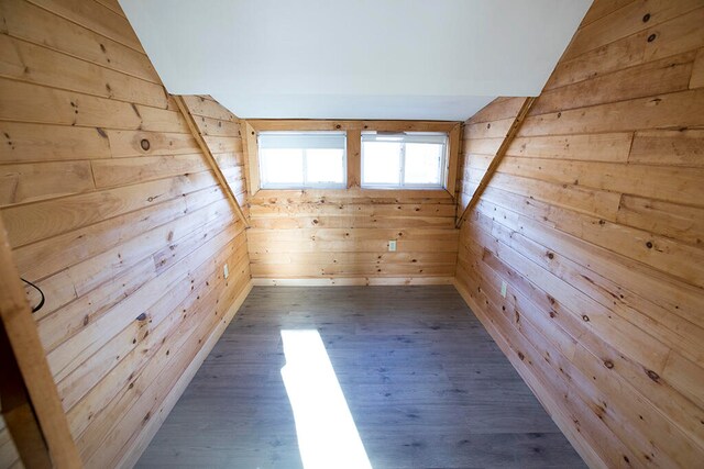 spare room with dark wood-type flooring, wood walls, and vaulted ceiling