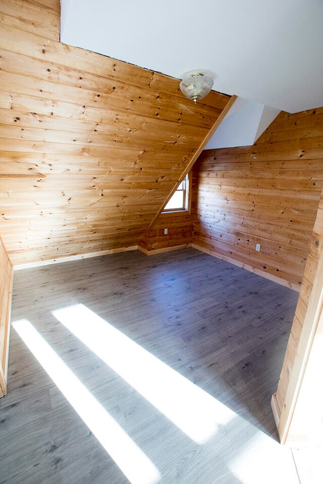 bonus room with hardwood / wood-style floors and vaulted ceiling