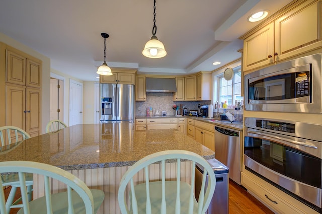 2 Maddox Pond Rd, Biddeford, ME 04005 - kitchen with stainless steel appliances, a breakfast bar, wall chimney exhaust hood, pendant lighting, and stone counters