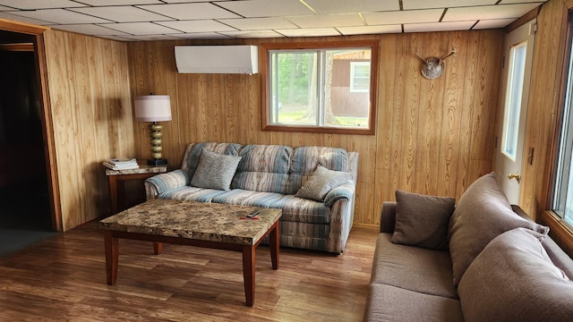 21 Greystone Ln Unit T4, Indian Purchase Twp, ME 04462 - living room featuring wooden walls, a wall mounted air conditioner, wood finished floors, and a paneled ceiling