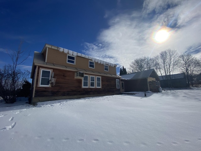 snow covered back of property featuring a wall mounted air conditioner