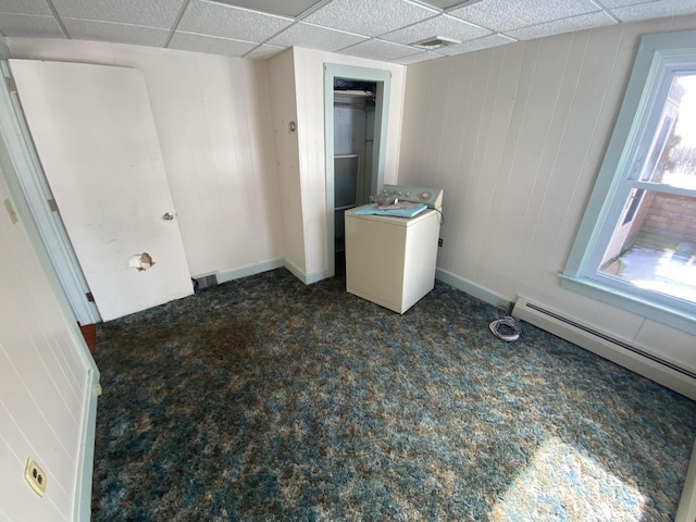 empty room with washer / clothes dryer, baseboard heating, dark colored carpet, and a paneled ceiling