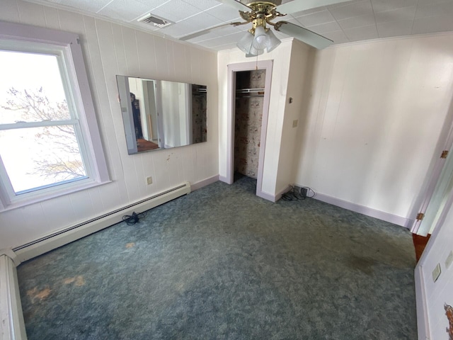 unfurnished bedroom with a closet, ceiling fan, dark colored carpet, and a baseboard heating unit