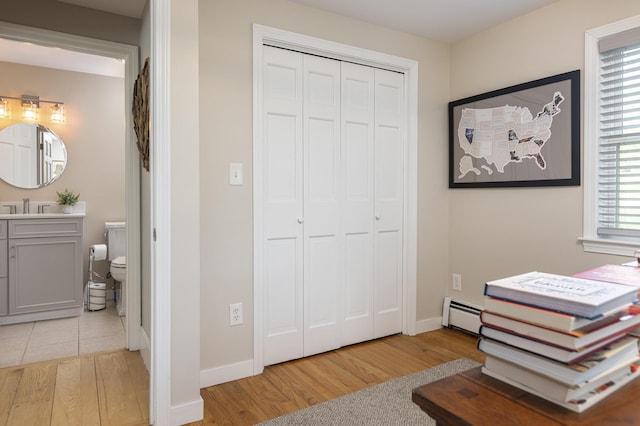 8 Hickory Ln, York, ME 03909 - bedroom featuring light wood-style flooring, a baseboard heating unit, a sink, and a closet