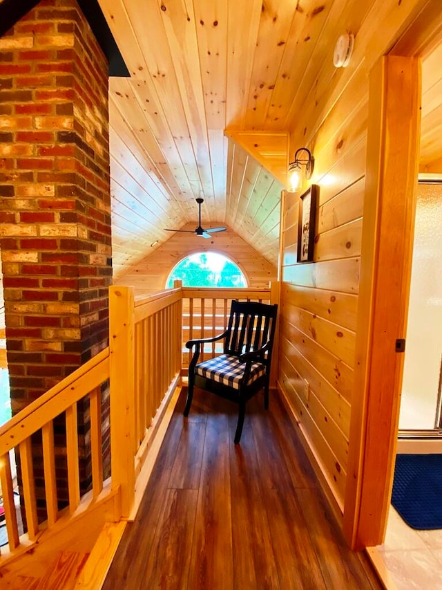 corridor with brick wall, hardwood / wood-style floors, wooden ceiling, wood walls, and vaulted ceiling