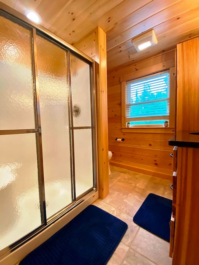 bathroom with toilet, a shower with shower door, wood ceiling, wooden walls, and tile floors